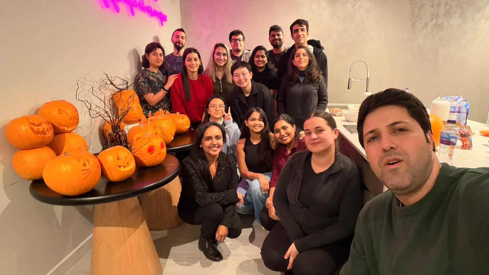 Group of DIFF_RENT residents smiling together beside a table of freshly carved pumpkins at the Harrow co-living building